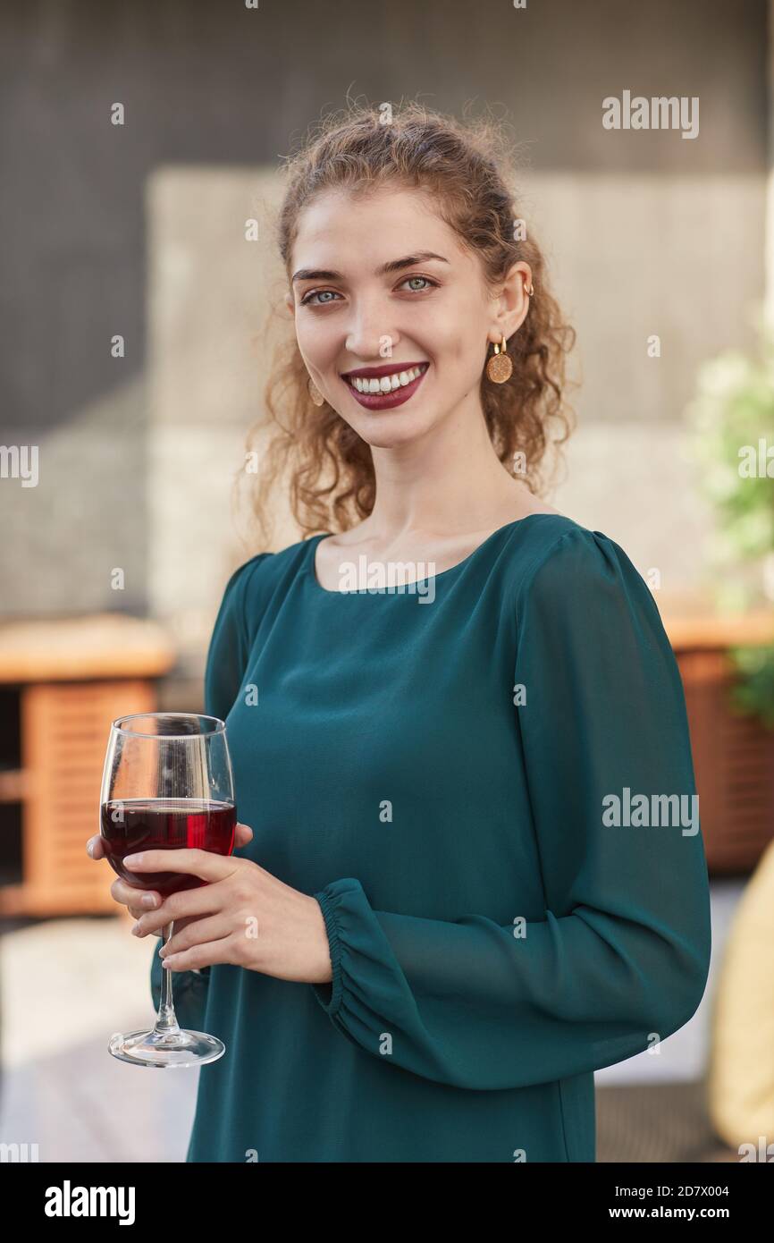 Vertikale Taille bis Porträt von lächelnden jungen Frau mit Wein Glas und Blick auf die Kamera, während Party im Freien genießen Stockfoto
