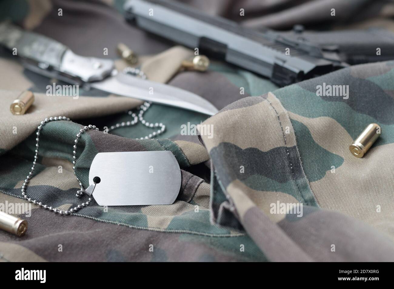 Arme-Dog-Tag-Token mit 9 mm Kugeln und Pistole liegen auf gefaltetem, tarngrünen Stoff. Ein Set von Militärveteranen oder Trophäen-Kit für alte Aufgaben Stockfoto