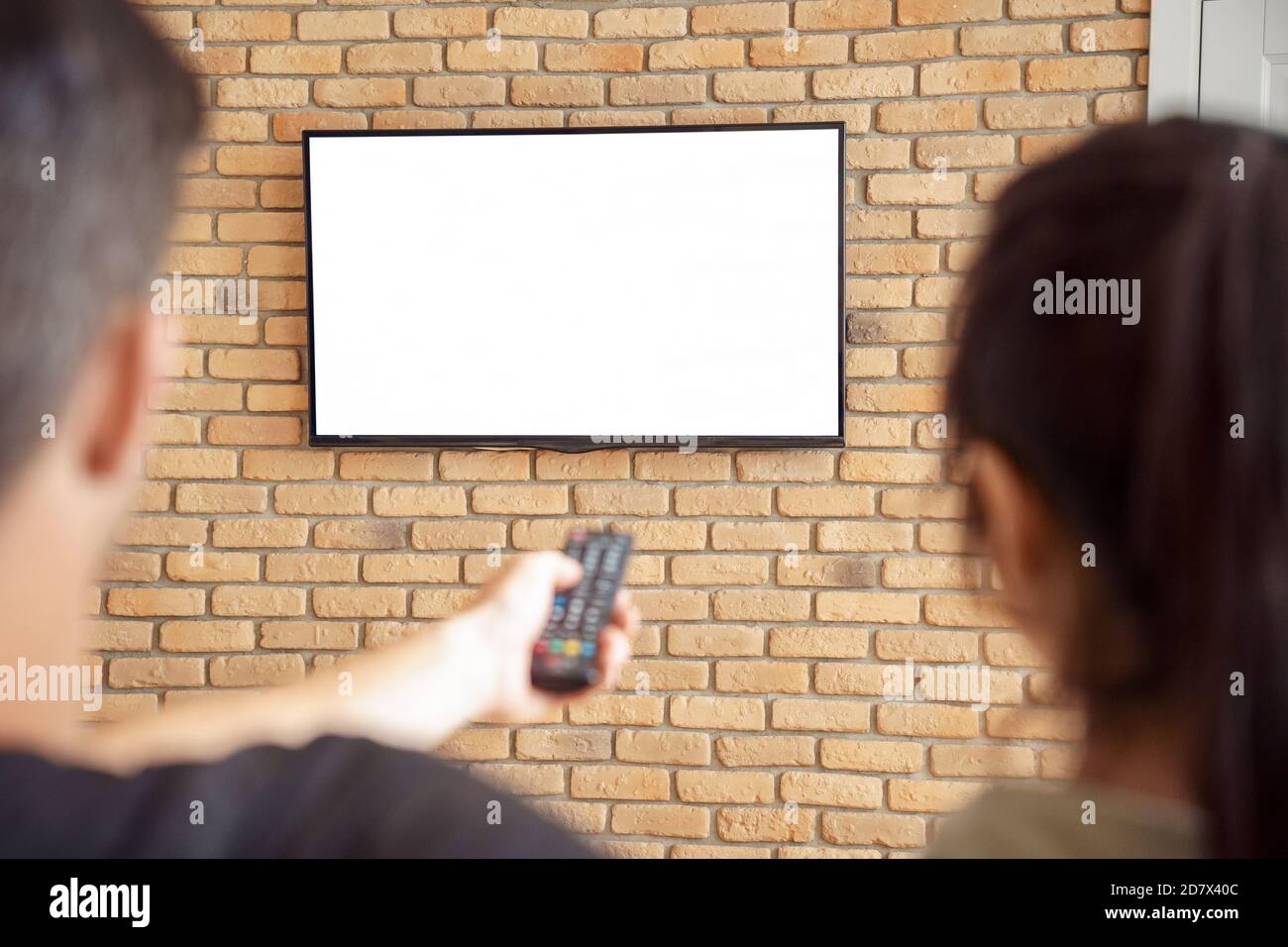 Paar halten Fernbedienung Fernsehen Mockup weißen Bildschirm zu Hause. Stockfoto