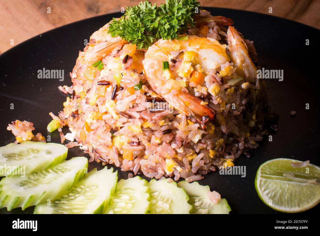 Gebratener Reis mit Garnelen serviert mit Gurke und Limette Stockfoto