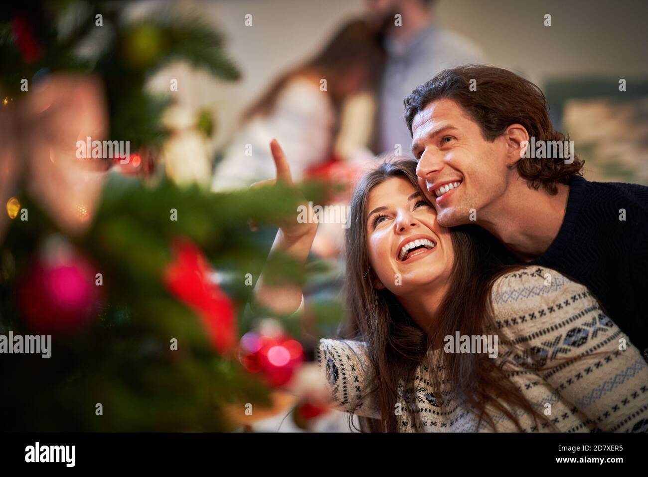 Erwachsene Paare haben Spaß über Weihnachtsbaum Stockfoto