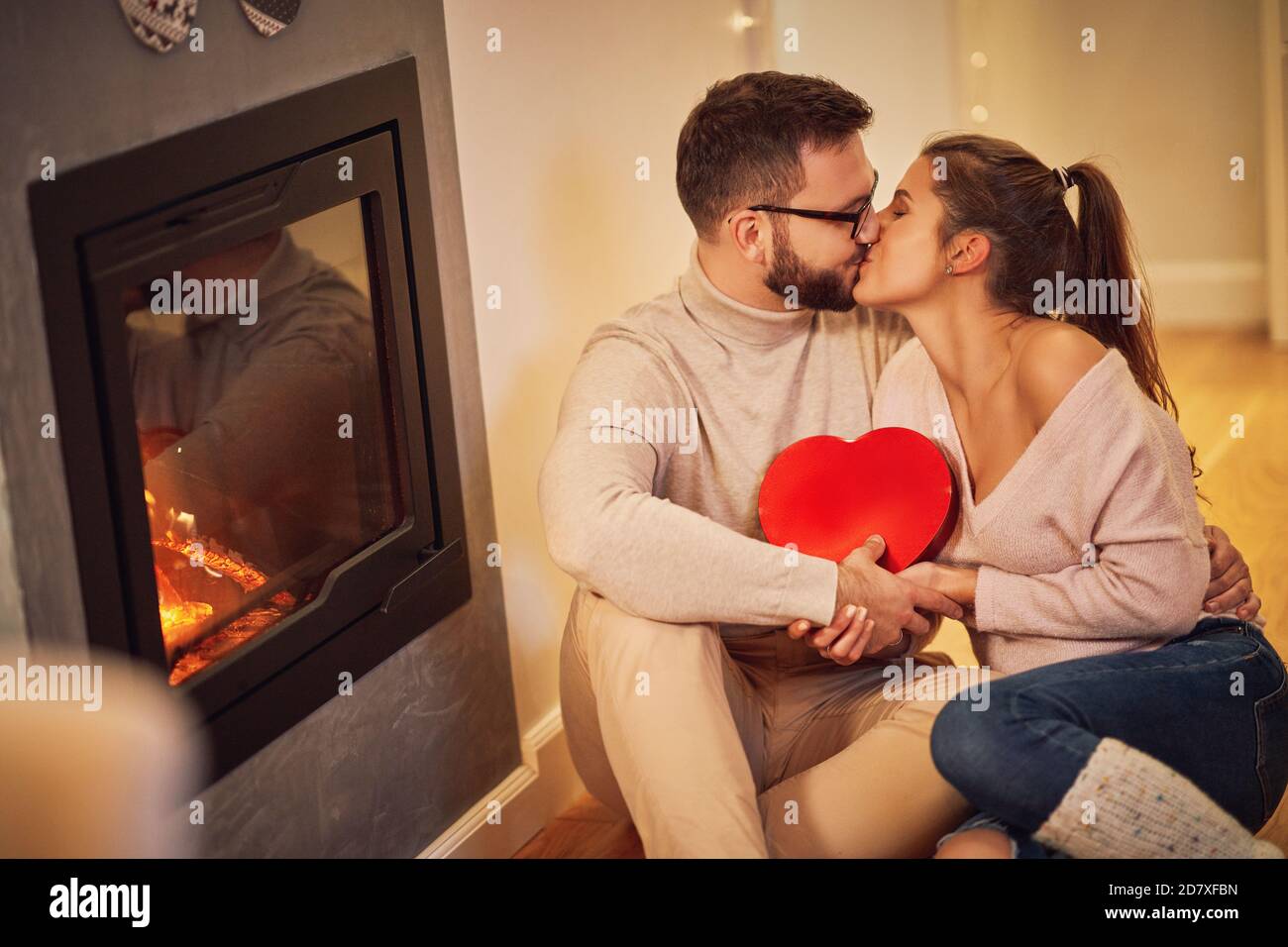 Erwachsenes Paar mit Geschenk über Kamin Stockfoto