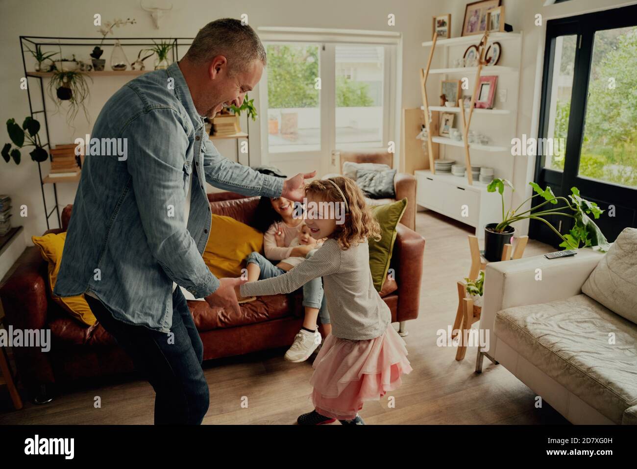 Fröhlicher Vater und Tochter spielen und tanzen zu Hause halten Hände Stockfoto