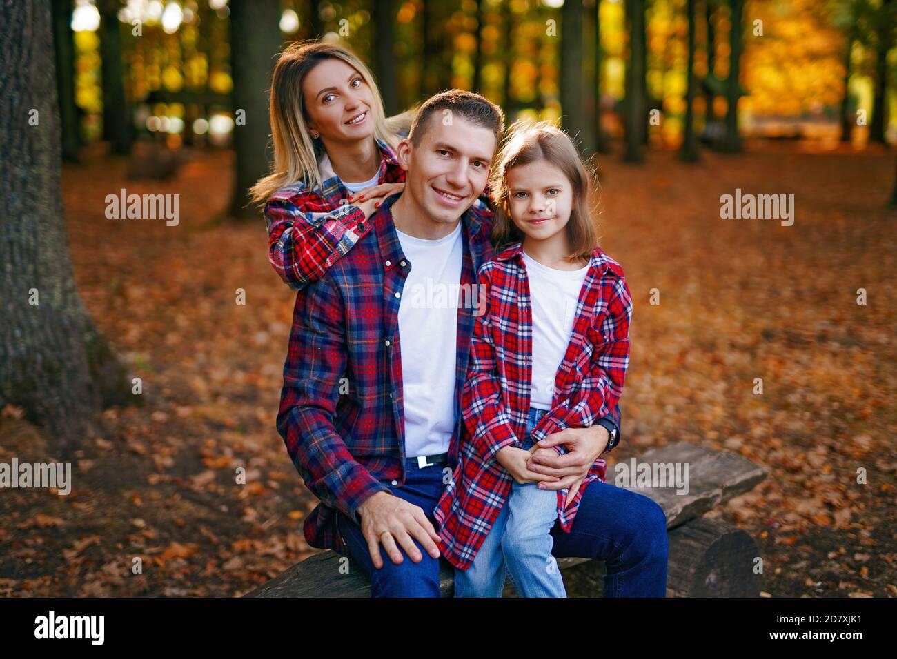 Foto einer wunderbaren Familie im Herbstwald auf einer Bank. Stockfoto