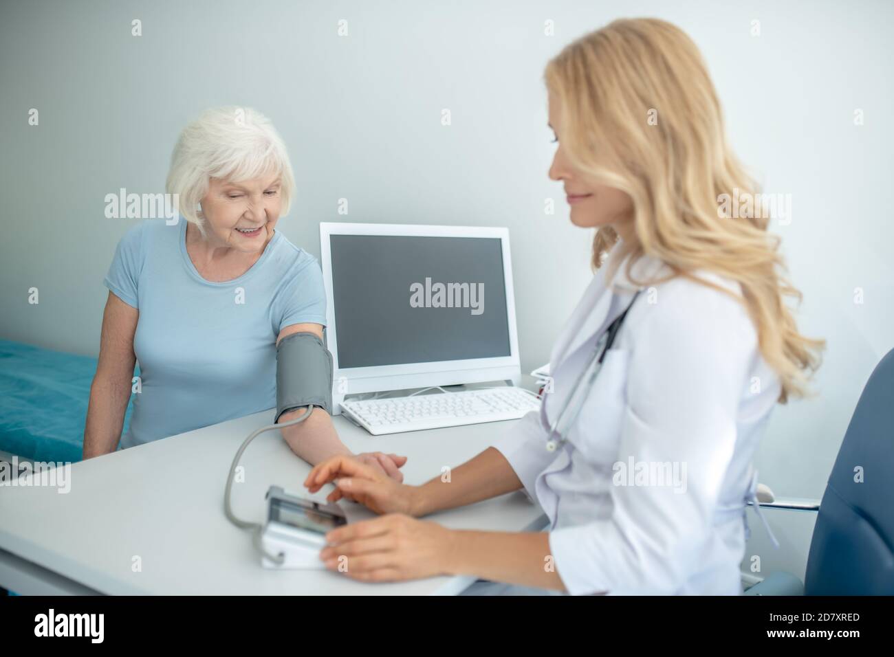 Kardiologin, die den Blutdruck an eine gut aussehende ältere Frau misst Stockfoto