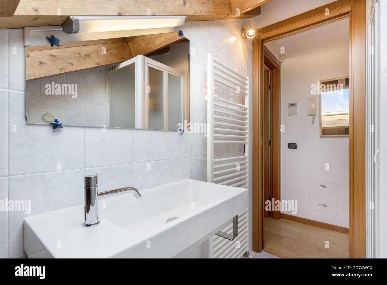 Praktisches und gemütliches Badezimmer mit Handtuchheizkörper, WC, Schrank und Waschbecken. Dach mit freiliegenden Holzbalken. Klassisches italienisches Design und Stil. Stockfoto