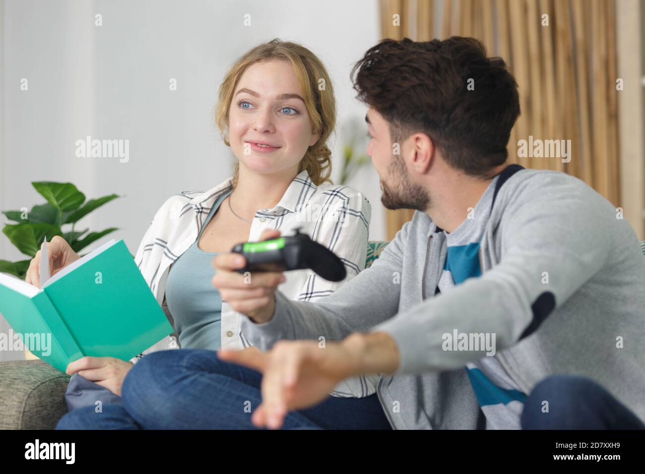 Mann spielt spannende Computerspiel, während Freundin Buch liest Stockfoto