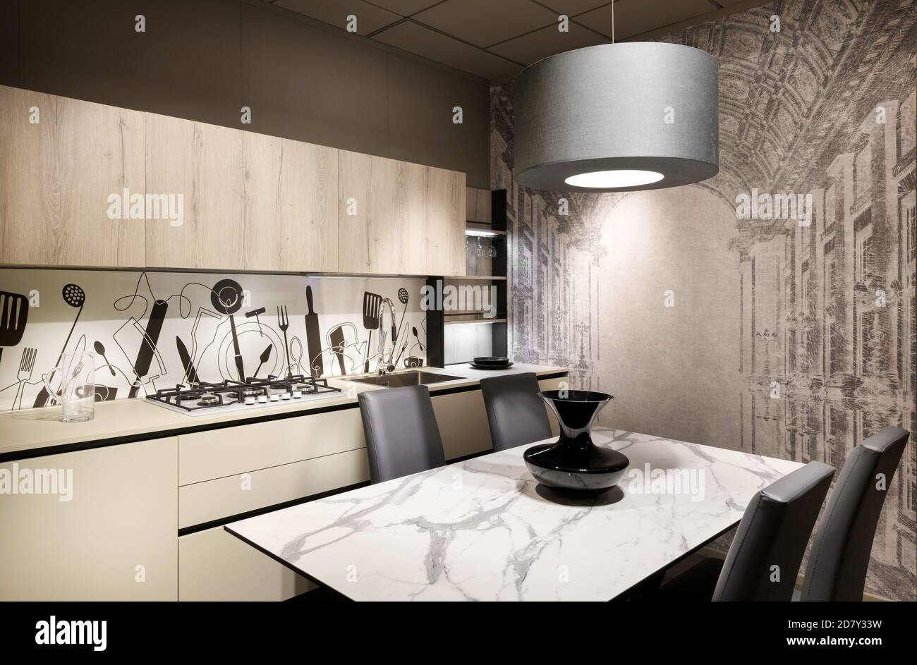 Moderne Einbauküche mit dekorativem Splash zurück und Wand mit Ein Esstisch und Stühle unter einer Hängeleuchte an der Decke Beleuchtung des Raumes Stockfoto