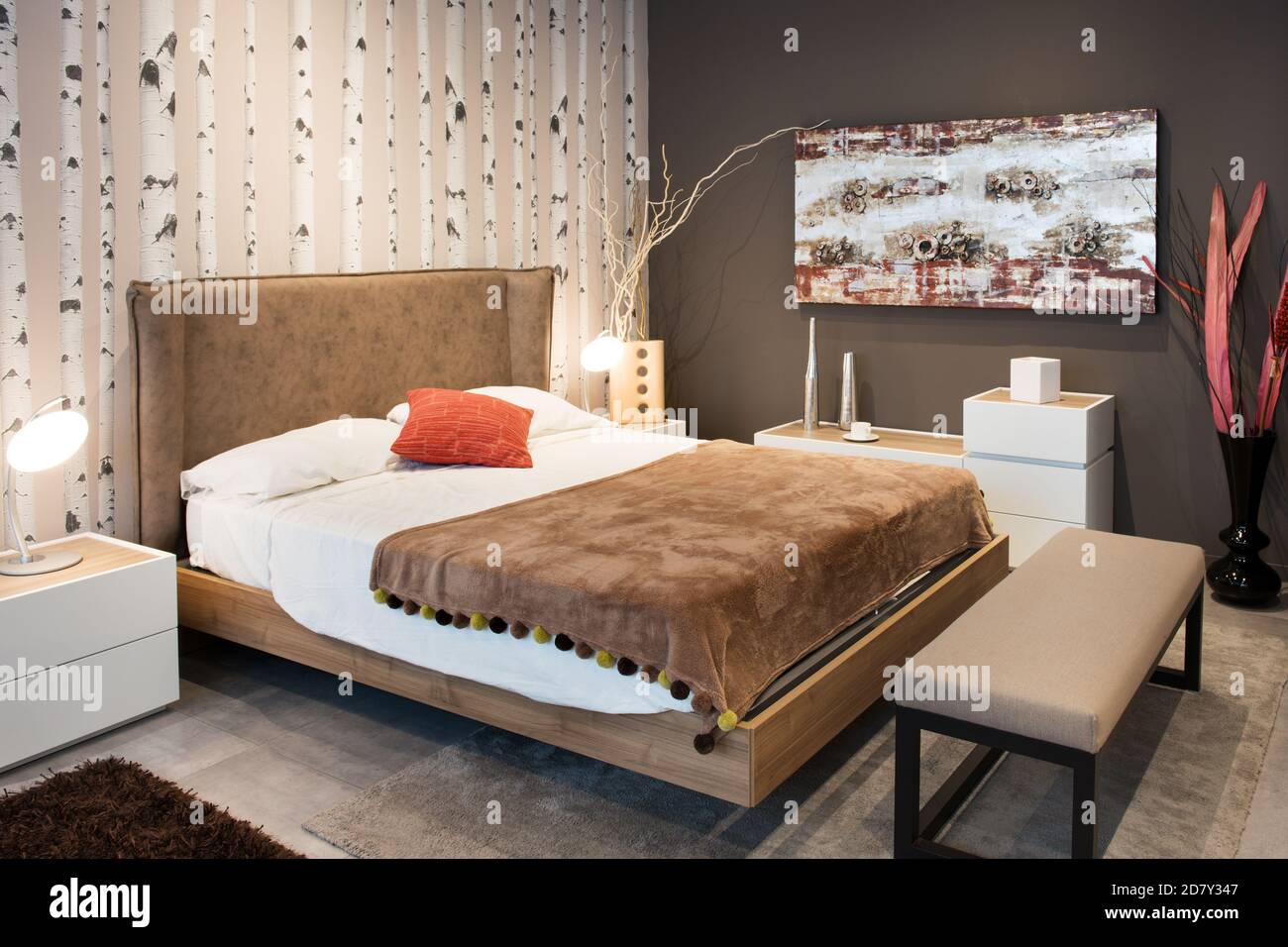 Interieur eines eleganten, modernen Schlafzimmers mit großem Doppeldiwan Stilbett mit gepolstertem braunem Kopfteil und Überwurf-Teppich mit Passende braune Tapete o Stockfoto