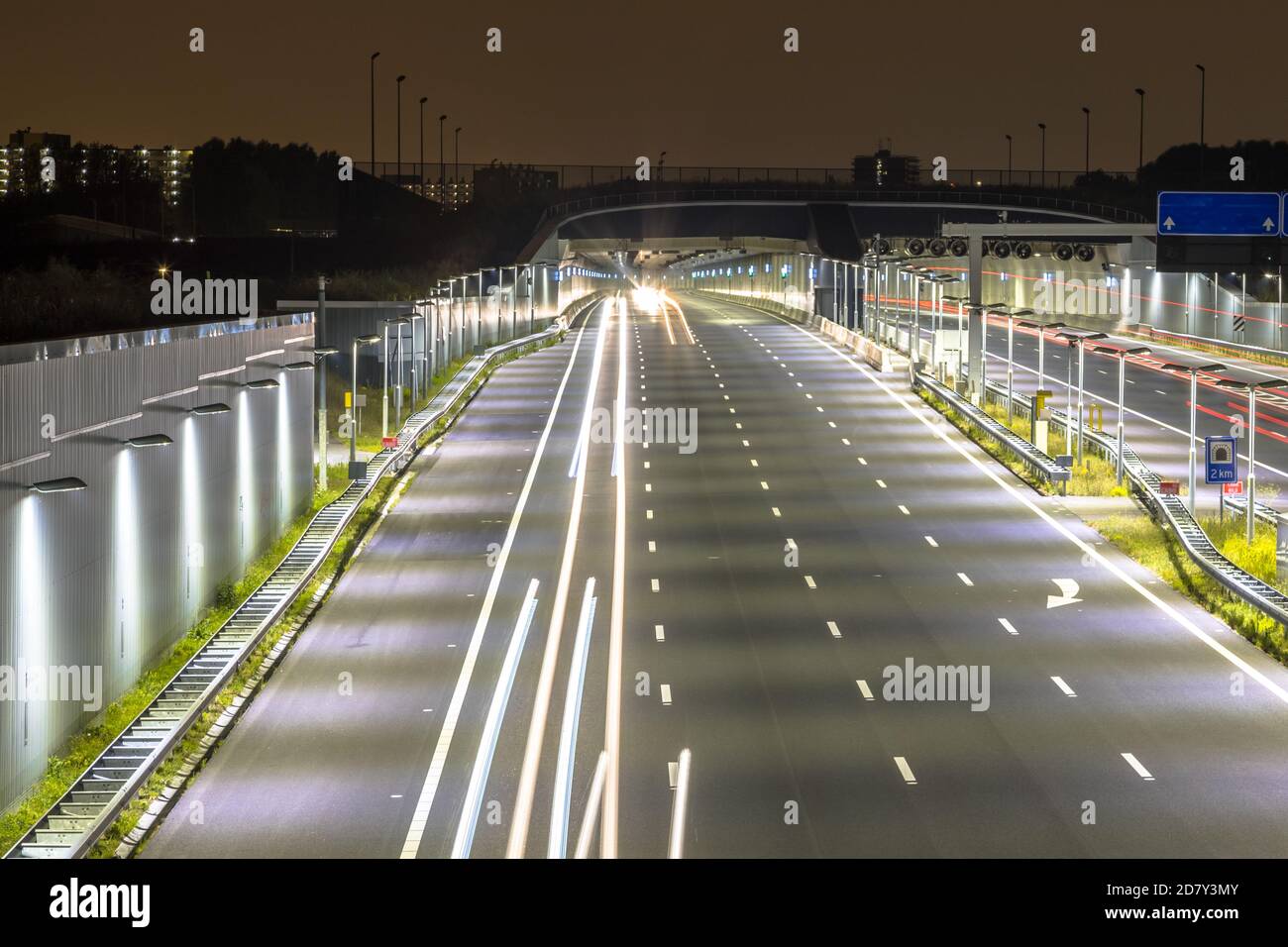 Autobahn mit Eingang des Tunnels in der Nacht mit verschwommenem Auto Leuchtet bei langer Belichtung Stockfoto