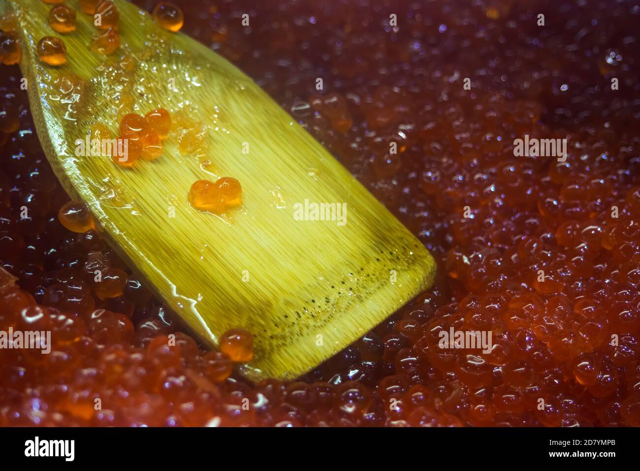 Nahaufnahme von rotem Kaviar und beigefarbenem Holzlöffel, selektiver Fokus. Stockfoto