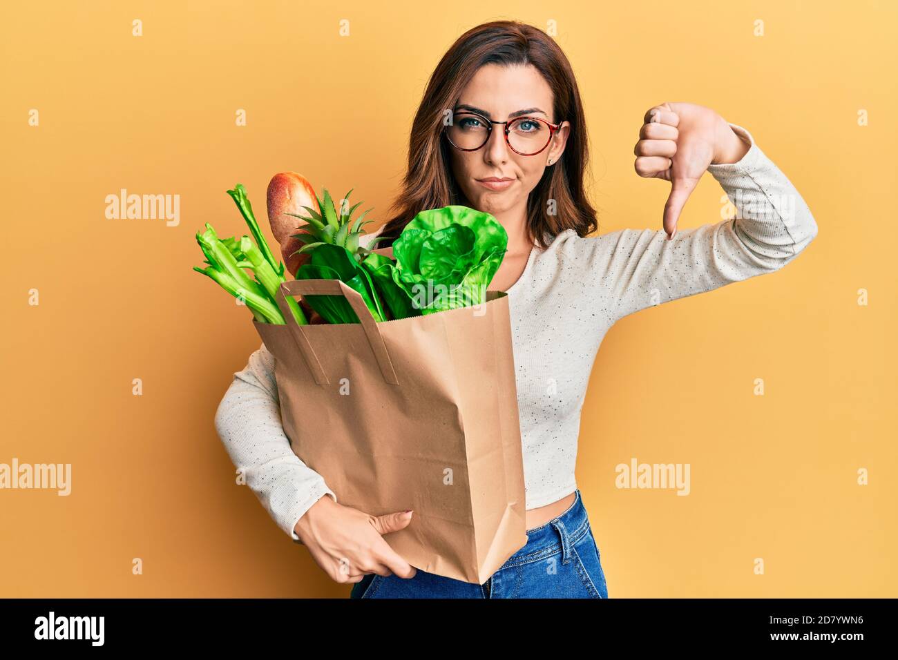 Junge Brünette Frau hält Papiertüte mit Brot und Lebensmittel mit ...