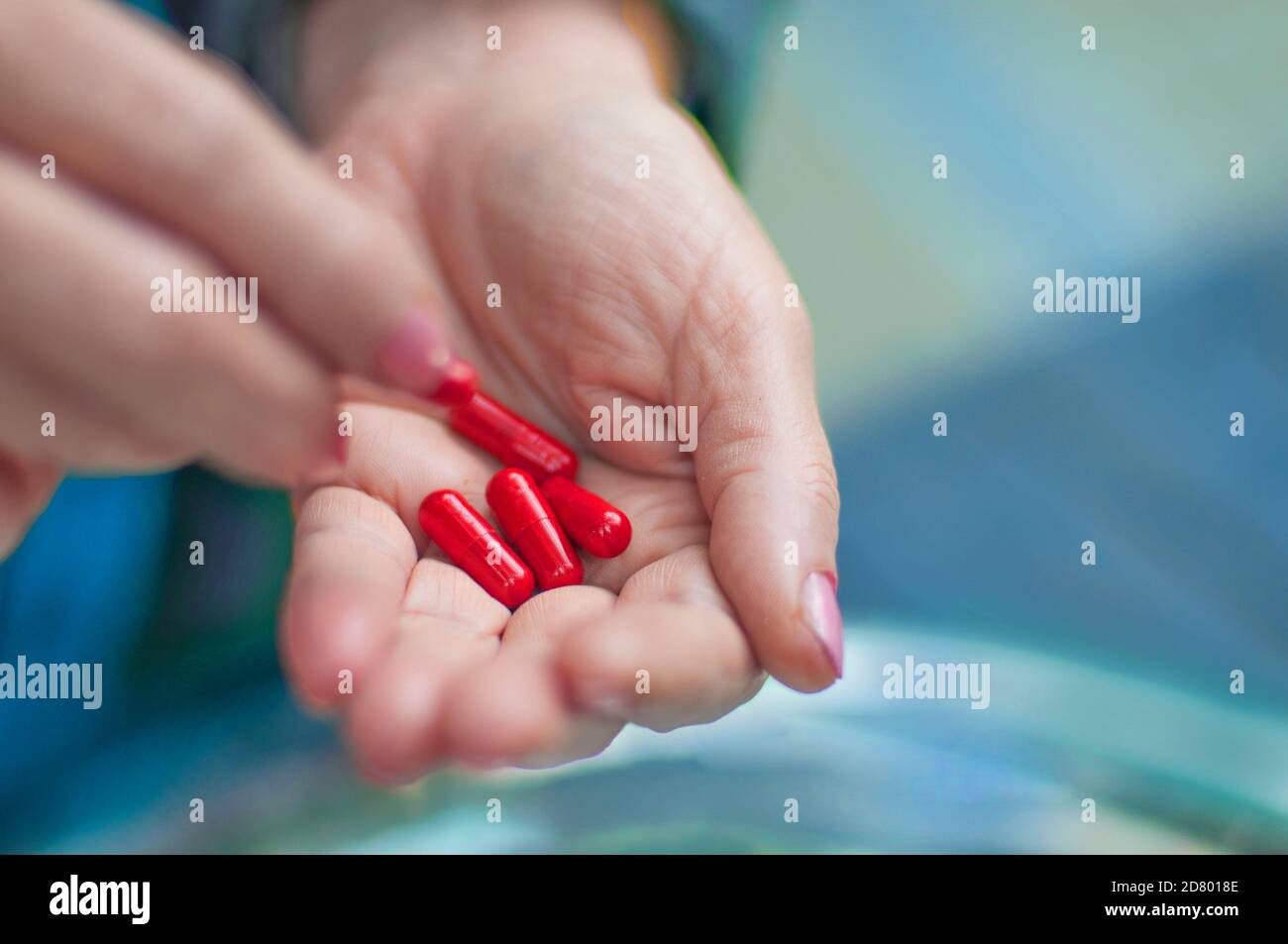 Hand hält wirksame rote antivirale oder antibakterielle Pillen (Penicillin) aus Pharmaunternehmen Stockfoto