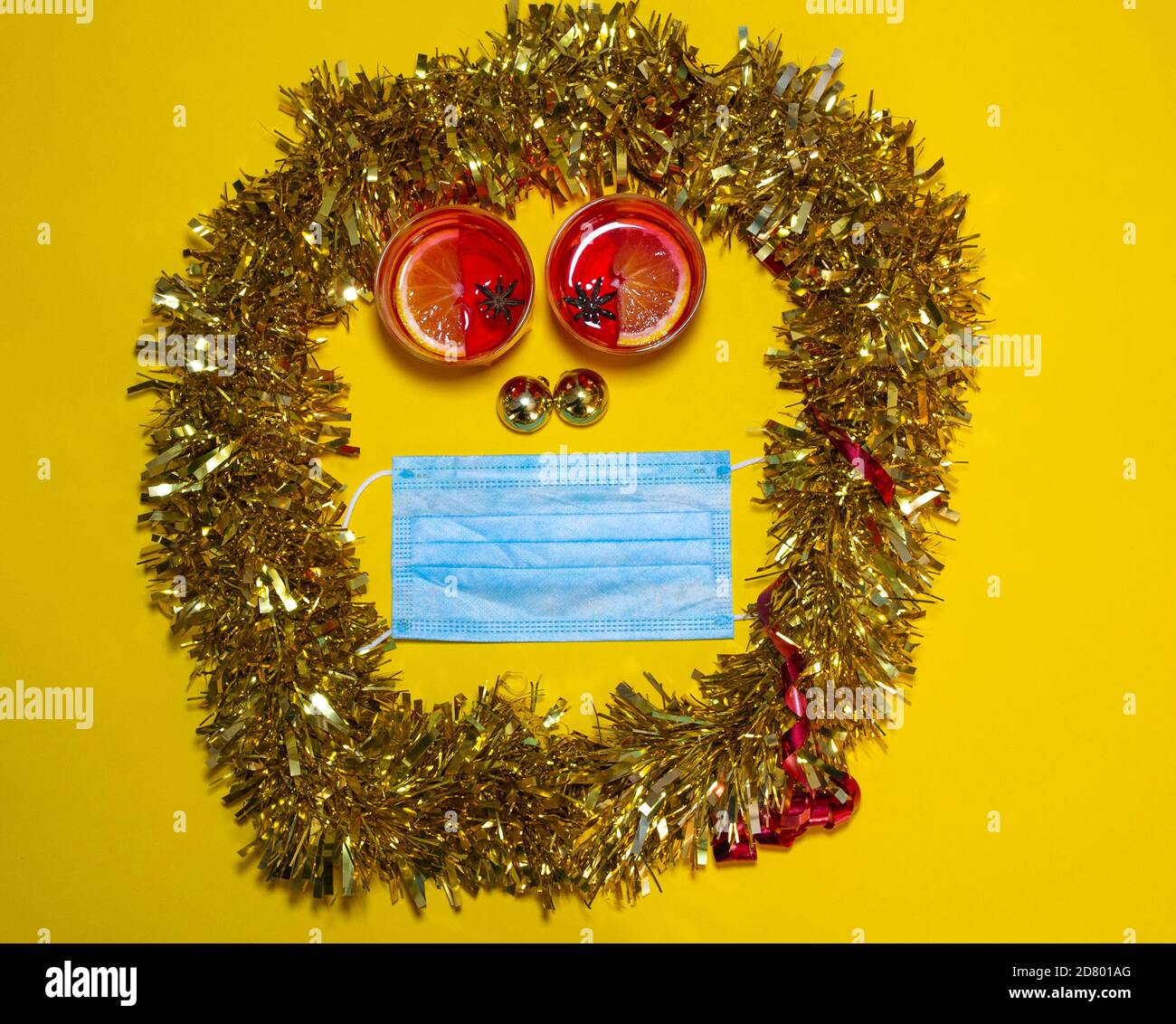 Overhead-Aufnahme einer einseitigen Komposition mit Gläsern Glühwein, Weihnachtskugeln und einer OP-Maske. Konzept der Weihnachtsfeier während der Th Stockfoto