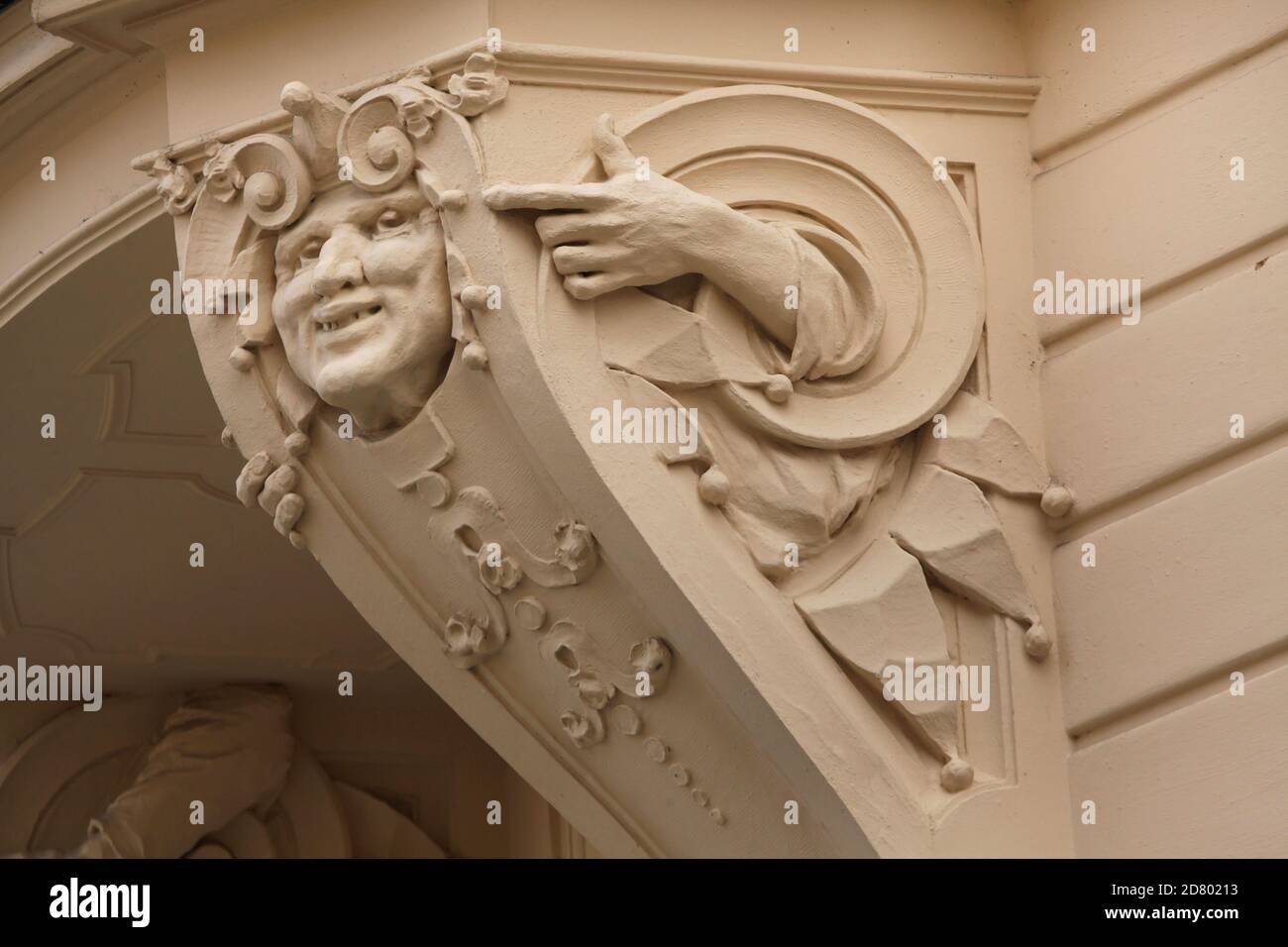Lustiges Maskaron mit Händen auf dem Eckfenster des Art Nouveau-Einnahmehauses in Prag, Tschechische Republik. Das Jugendstilgebäude des tschechischen Architekten Osvald Polívka mit Stuckverzierungen des tschechischen Bildhauers Antonín Popp wurde 1903 an der Ecke der Straßen Vojtěšská und Na Struze in Nové Město (Neustadt) erbaut. Stockfoto