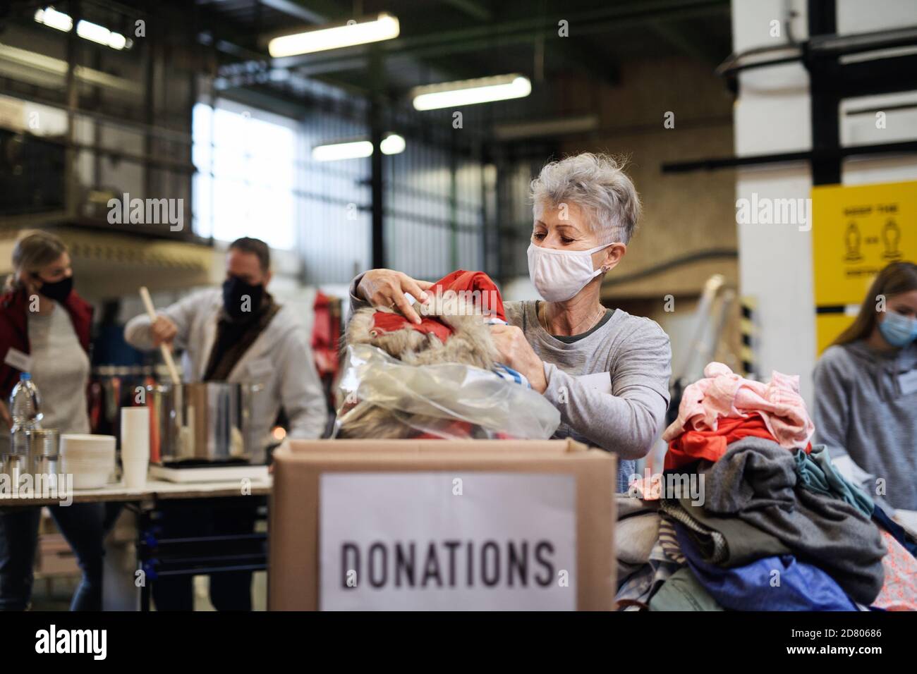 Freiwillige arbeiten mit Lebensmitteln und Kleidung in der Gemeinde Wohltätigkeitsspenden Zentrum, coronavirus Konzept. Stockfoto