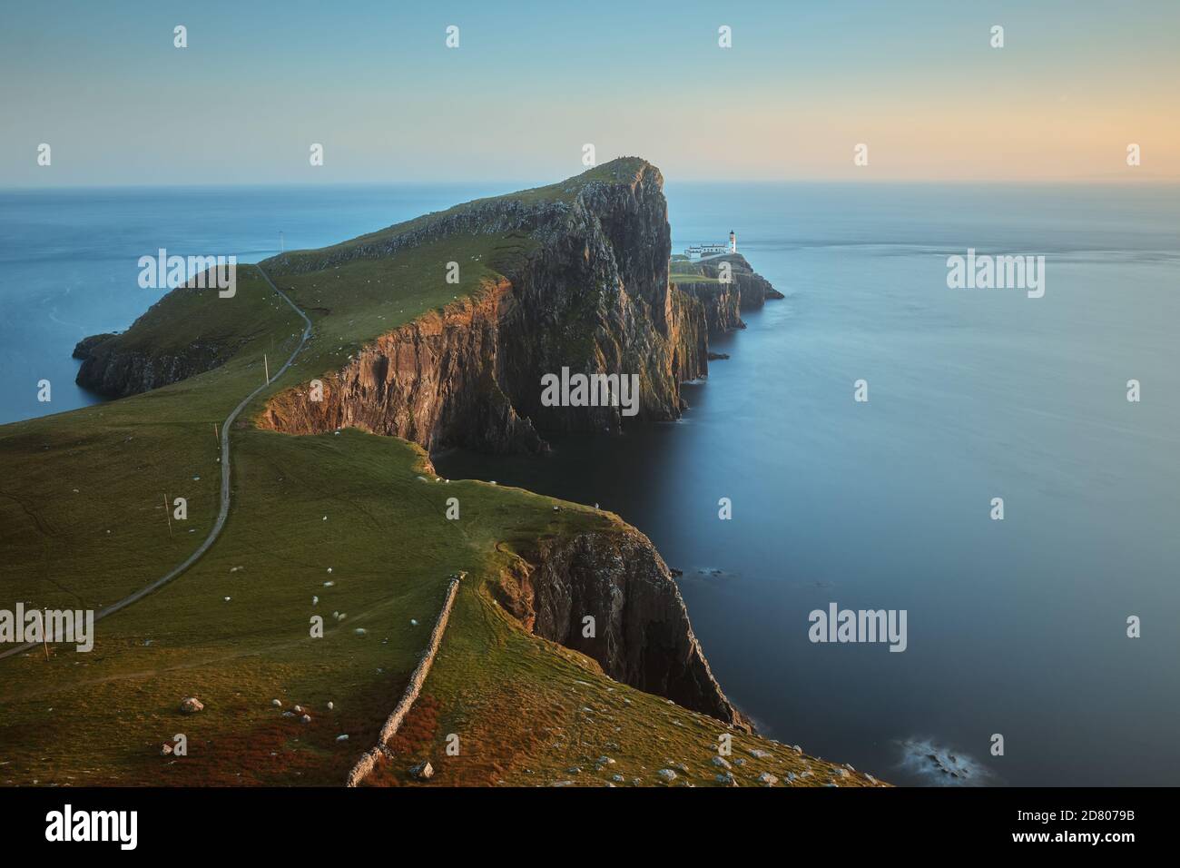 Eine Landschaft eines feinen Leuchtturms, der auf einer atemberaubenden Klippe vor dem Hintergrund des Meeres steht und von der untergehenden Sonne beleuchtet wird. Neist Point, Isle of Skye, Schottland Stockfoto