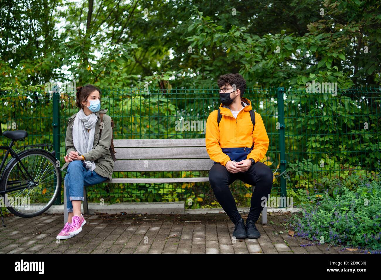Junge Leute sprechen auf der Bank im Freien in der Stadt. Coronavirus und sicheres Entfernungskonzept. Stockfoto