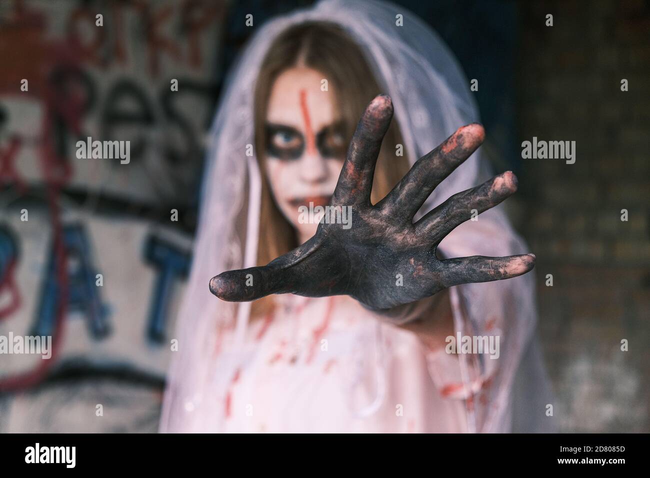 Horror, Alptraum und Halloween Konzept. Tote Braut. Junge Frau im Zombie Make-up mit Braut Schleier auf dem Kopf schaut in die Kamera reichen ihre Hand f Stockfoto