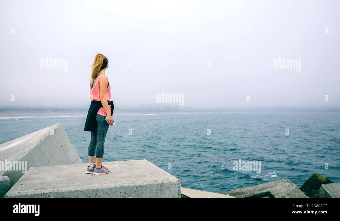 Junge Frau auf konkrete Baustein auf das Meer Stockfoto