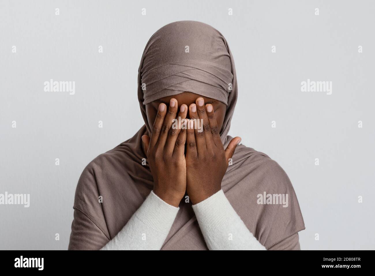 Muslimische Diskriminierung. Verängstigte schwarze islamische Frau in Hijab, die Gesicht mit Händen bedeckt Stockfoto