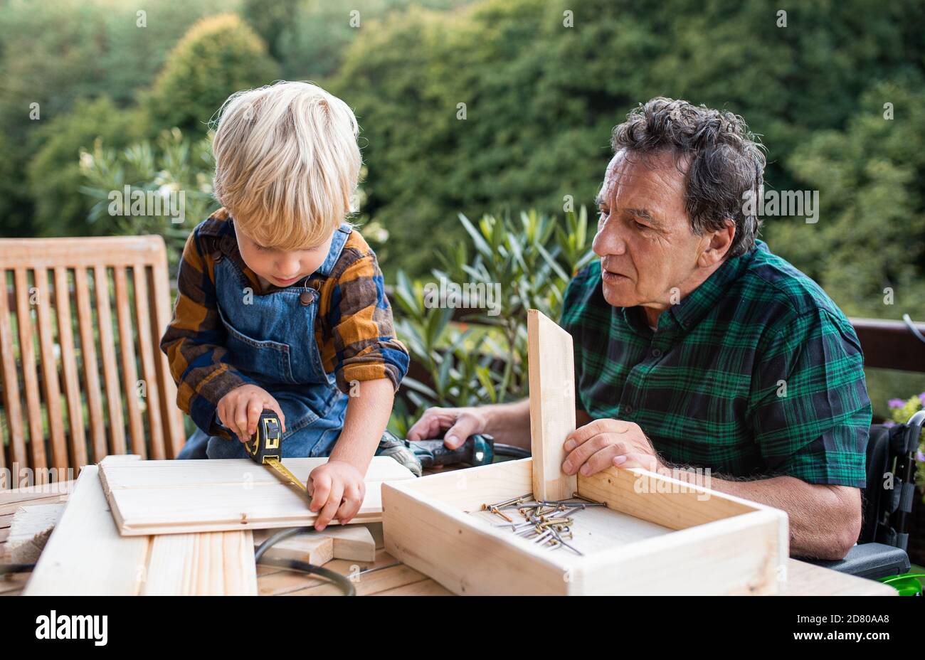 Kleiner Junge mit Senior Großvater im Rollstuhl Bau Vogelhaus, diy-Projekt. Stockfoto