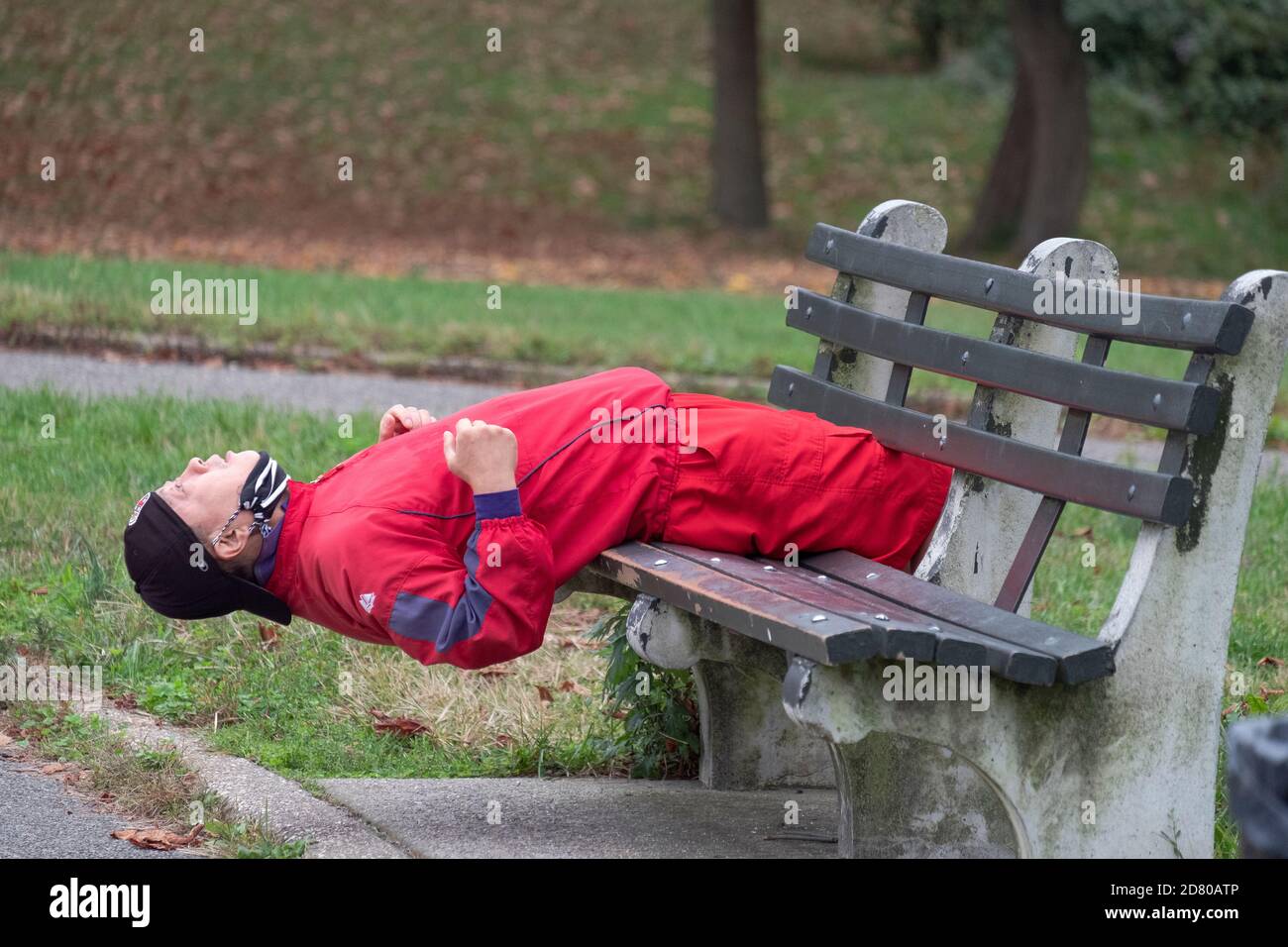 Ein asiatischer amerikanischer Mann übt, indem er Sit-ups auf einer Bank in einem Park in Flushing, Queens, New York, macht. Stockfoto