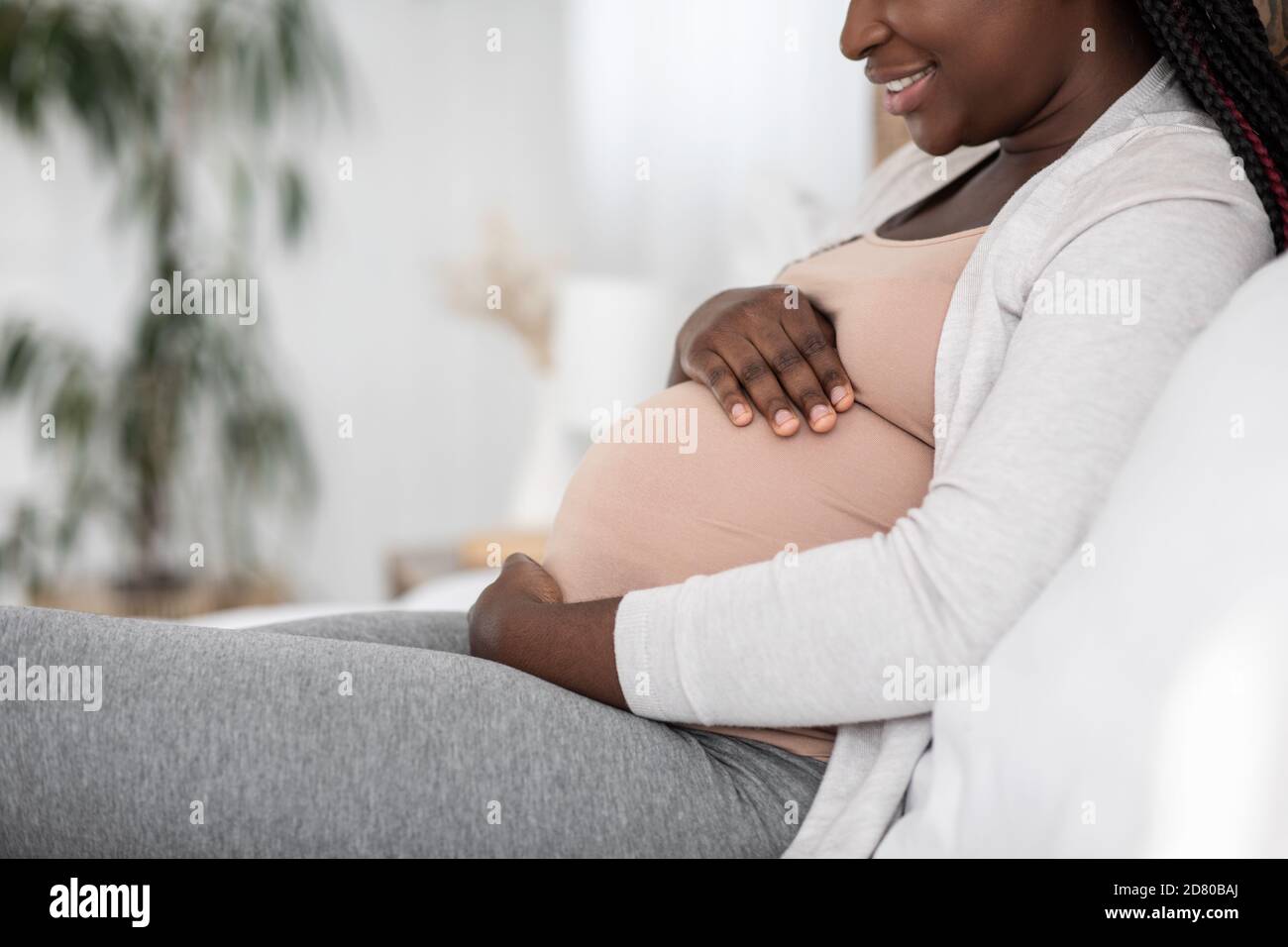 Schwarze Schwangere Frau Auf Dem Bett Sitzend Am Umarmenden Bauch, Seitenansicht Stockfoto