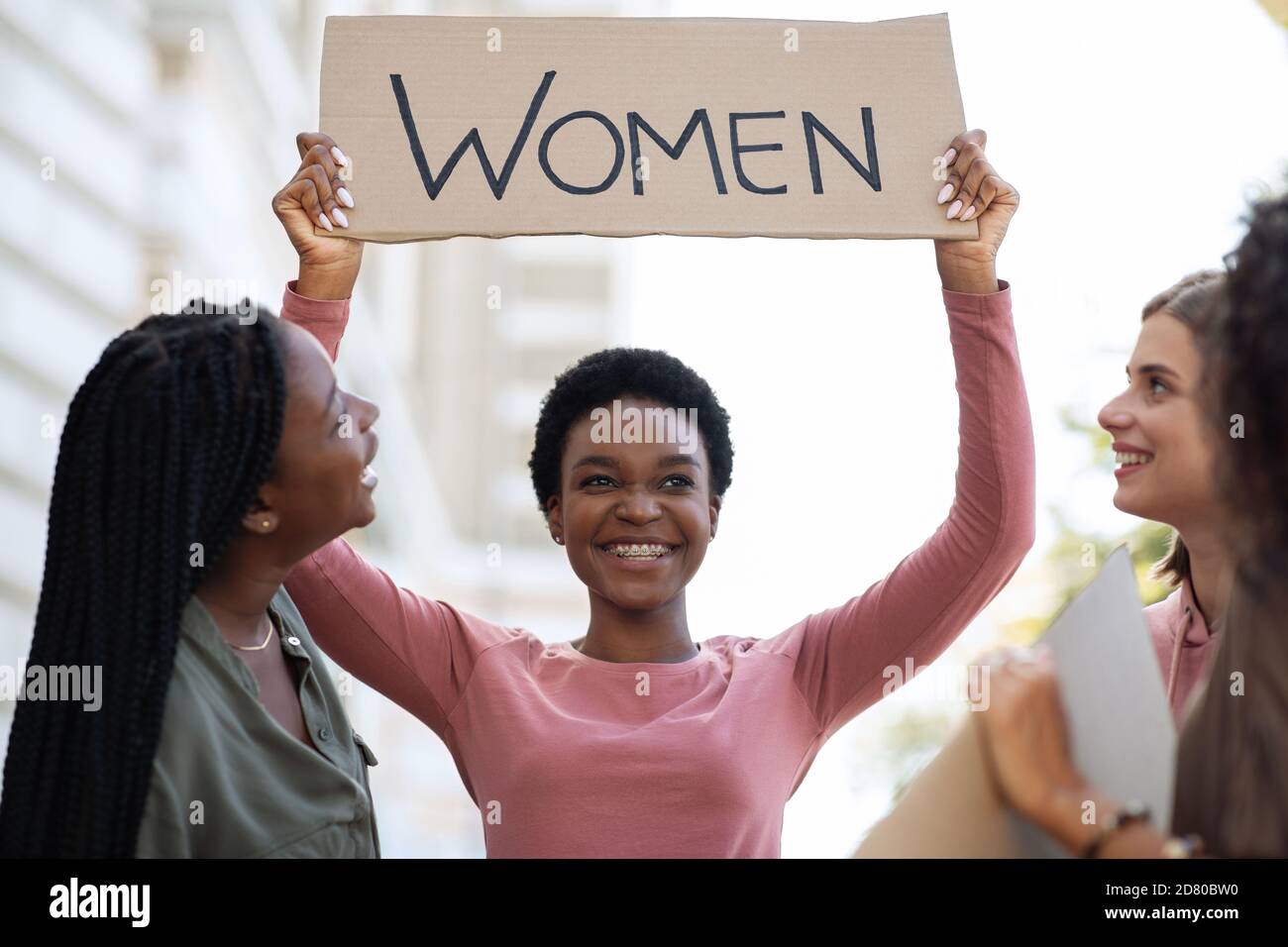 Fröhliche schwarze Frau mit Plakat, für Frauenrechte kämpfen Stockfoto