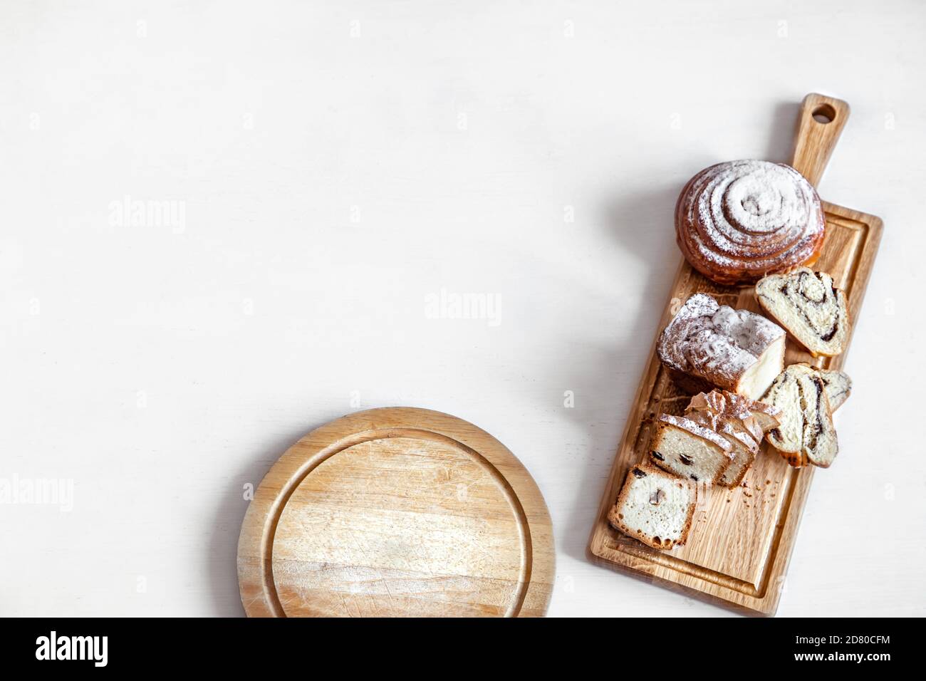 Verschiedene frische Backwaren werden auf einem Holzstab geschnitten. Auf einem hellen Hintergrund Platz für Text. Stockfoto