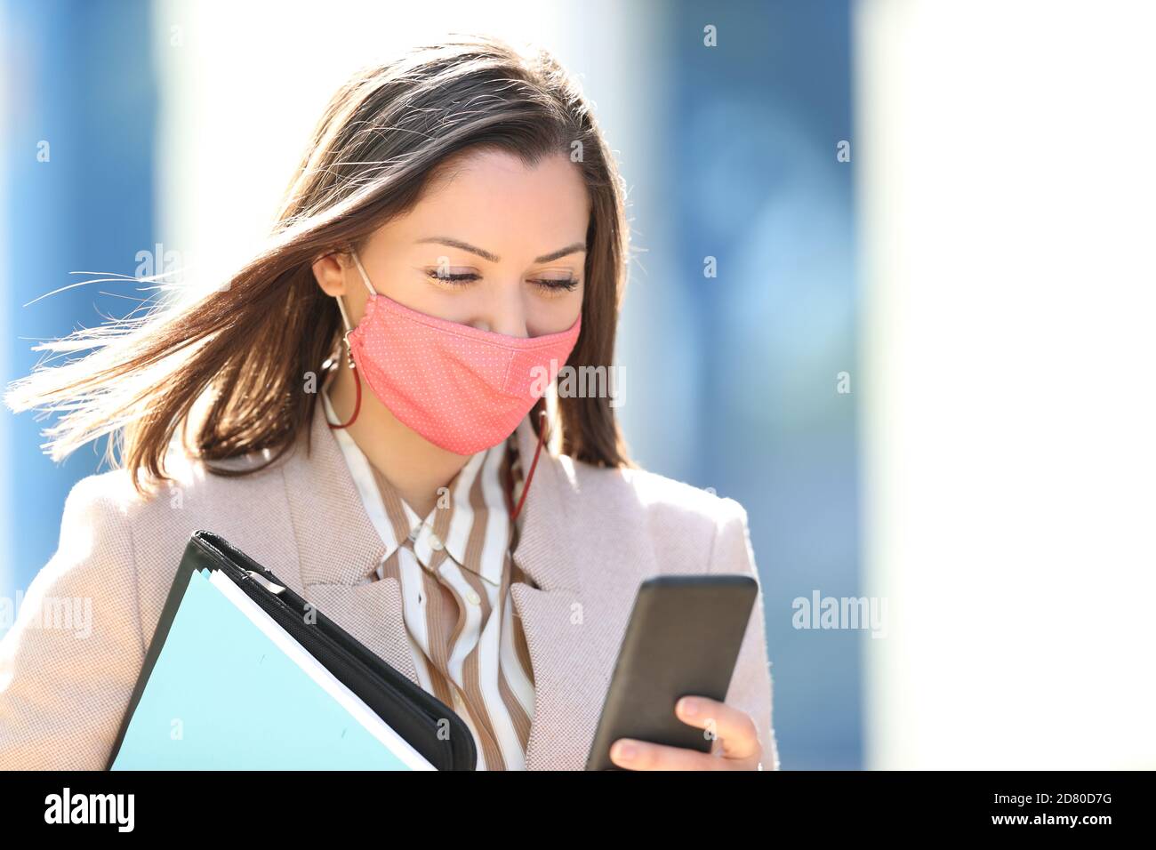 Geschäftsfrau trägt Maske Vermeidung Coronavirus Lesen Smartphone Inhalt zu Fuß Auf der Straße Stockfoto