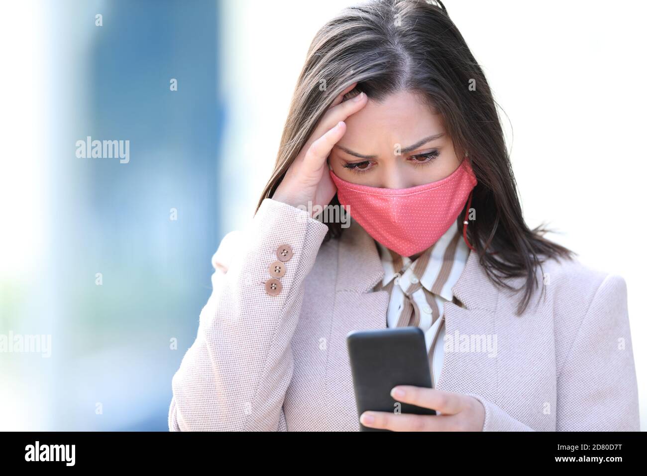 Besorgt Geschäftsfrau mit Maske lesen Smartphone-Inhalt in Coronavirus Timer Stockfoto
