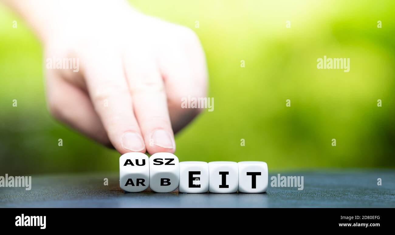 Hand dreht Würfel und ändert das deutsche Wort 'Arbeit' in 'Auszeit'. Stockfoto