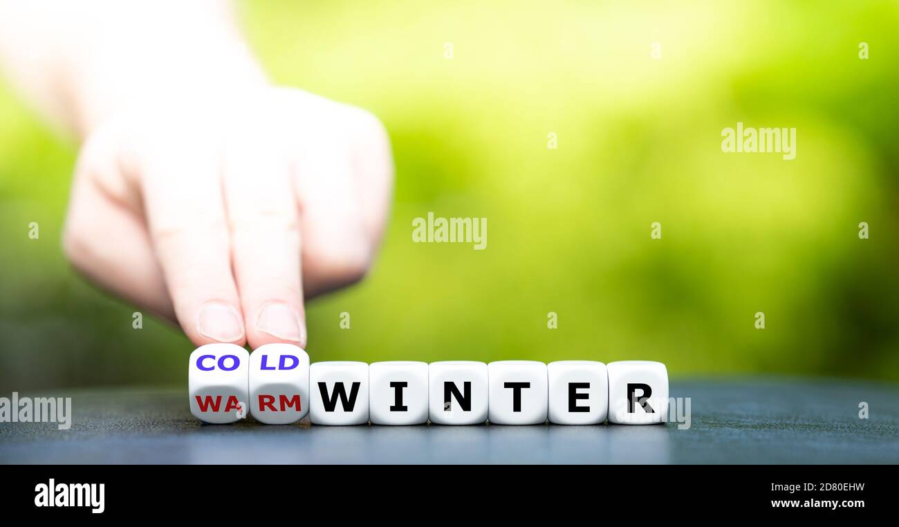 Die Vorzeit für einen kalten Winter. Die Hand dreht Würfel und ändert den Ausdruck 'warmer Winter' in 'kalter Winter'. Stockfoto