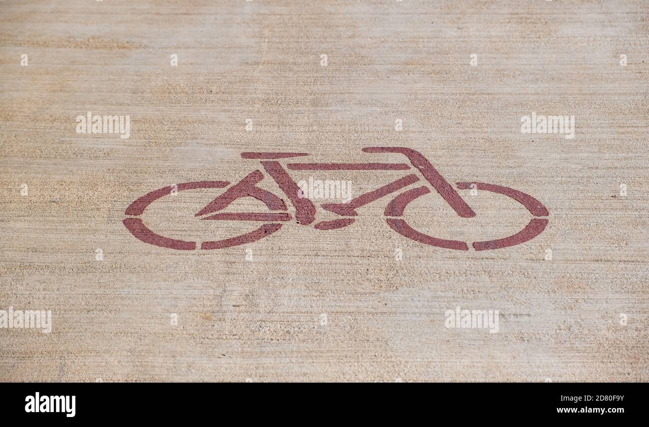 Konzept der Fahrradspur. Fahrrad rotes Schild auf beige Asphaltweg. Prioritärer Sicherheitsweg für Radfahrer. Gesunder Lebensstil mit Aktivitäten, Sport Stockfoto