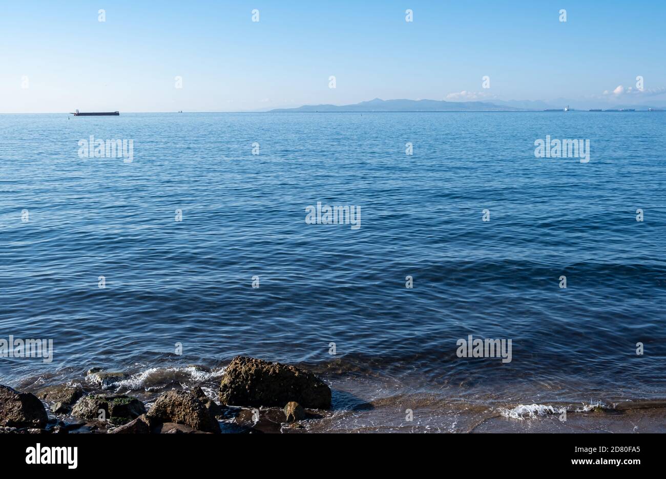 Drapetsona alter Hafen, Piräus, Griechenland. Silhouette von Frachtschiffen und Booten. Blick vom Strand auf festverankerte Schiffe im Hintergrund. Blauer Himmel und Meer eine sonnige da Stockfoto