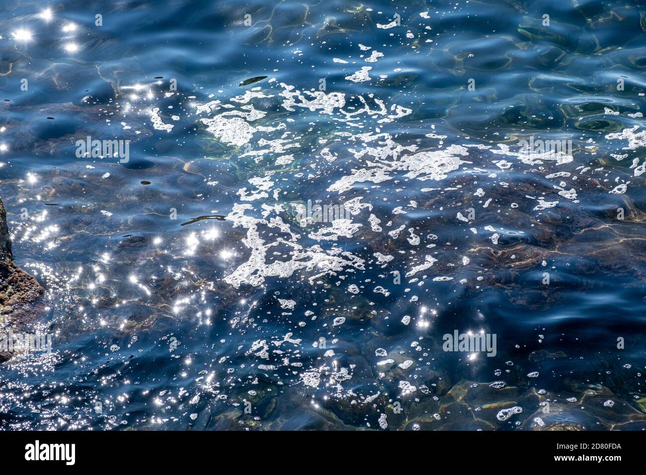 Konzept der Meeresverschmutzung. Schaum auf der sonnigen Wasseroberfläche, Öl, Erdöl, Chemikalien. Kein Ort für Leben ist das Ergebnis von Umweltschäden. Stockfoto