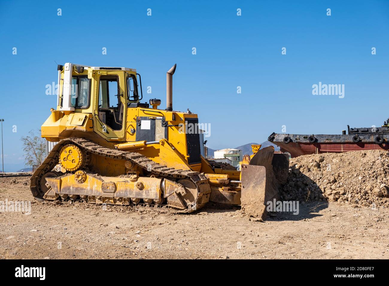 Gelbe Planierraupe auf Drapetsona Werft, Piräus, Griechenland. Schwere Bagger, Schaufel, Bagger, Bagger Fahrzeug. Schiff, blauer Himmel Hintergrund. Stockfoto