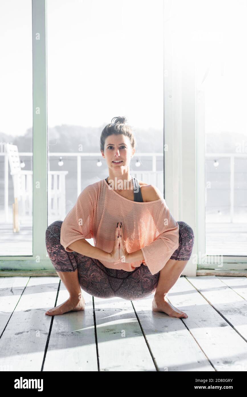 Frau übt Girlande Pose während ihrer Yoga-Klasse Stockfoto