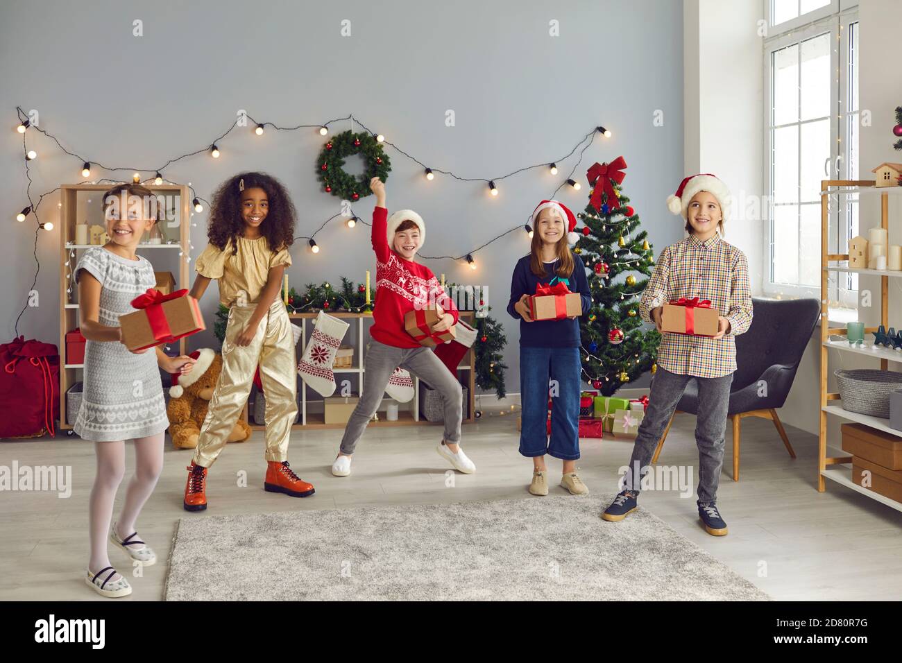 Glückliche Kinder halten ihre Weihnachtsgeschenke und Spaß an Gemütliche Party zu Hause Stockfoto