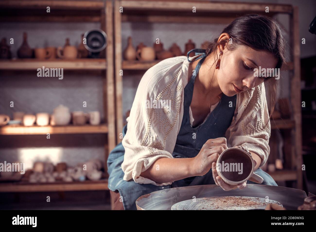 Stylishpotter weibliche Student Bildhauer arbeitet mit Ton auf einem Potter-Rad und am Tisch mit den Werkzeugen. Handgefertigt. Stockfoto