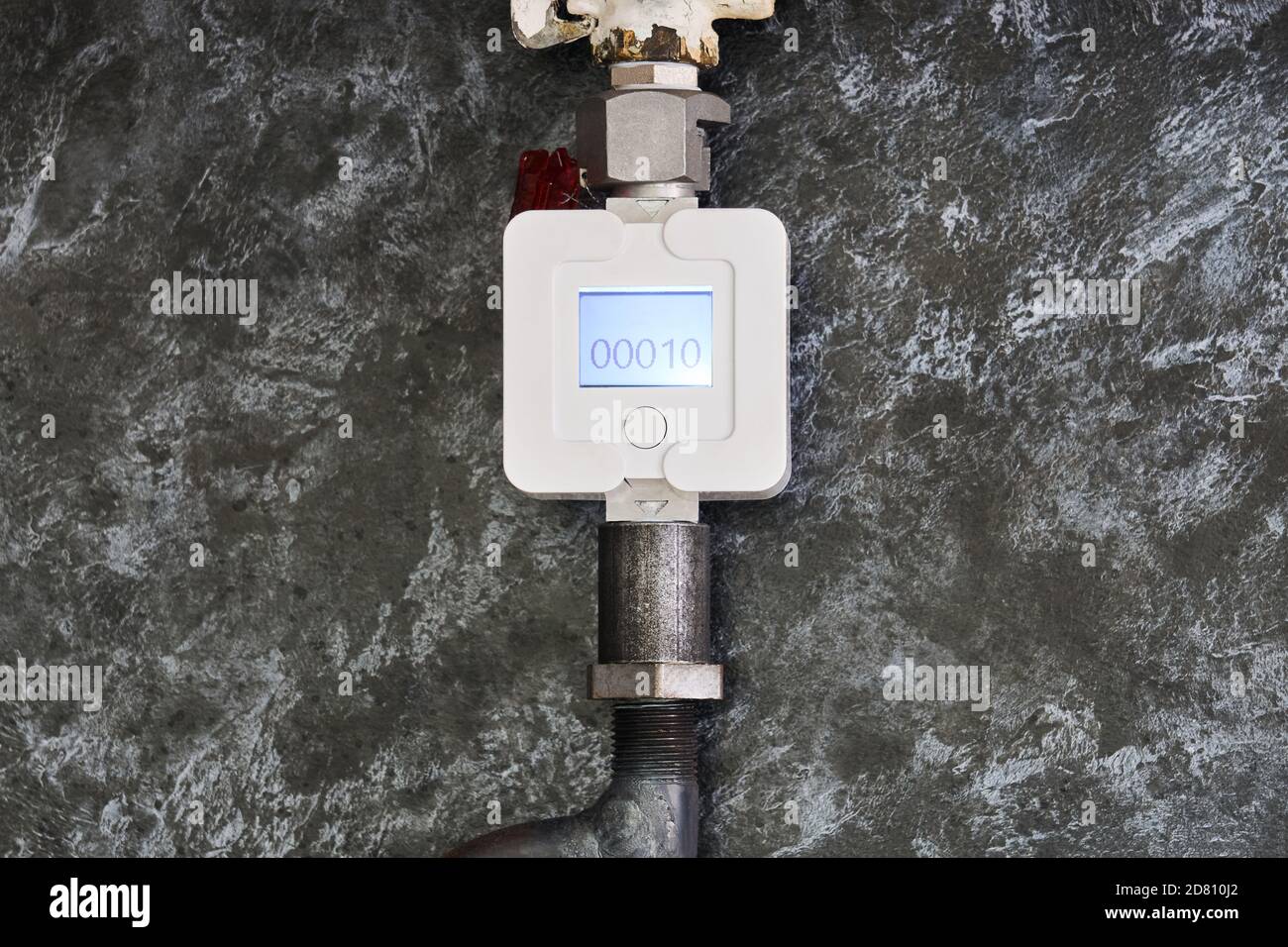 Der Gaszähler für den Haushalt ist an einem Rohr im installiert Küche vor dem Hintergrund einer dekorativen Platte Stockfoto