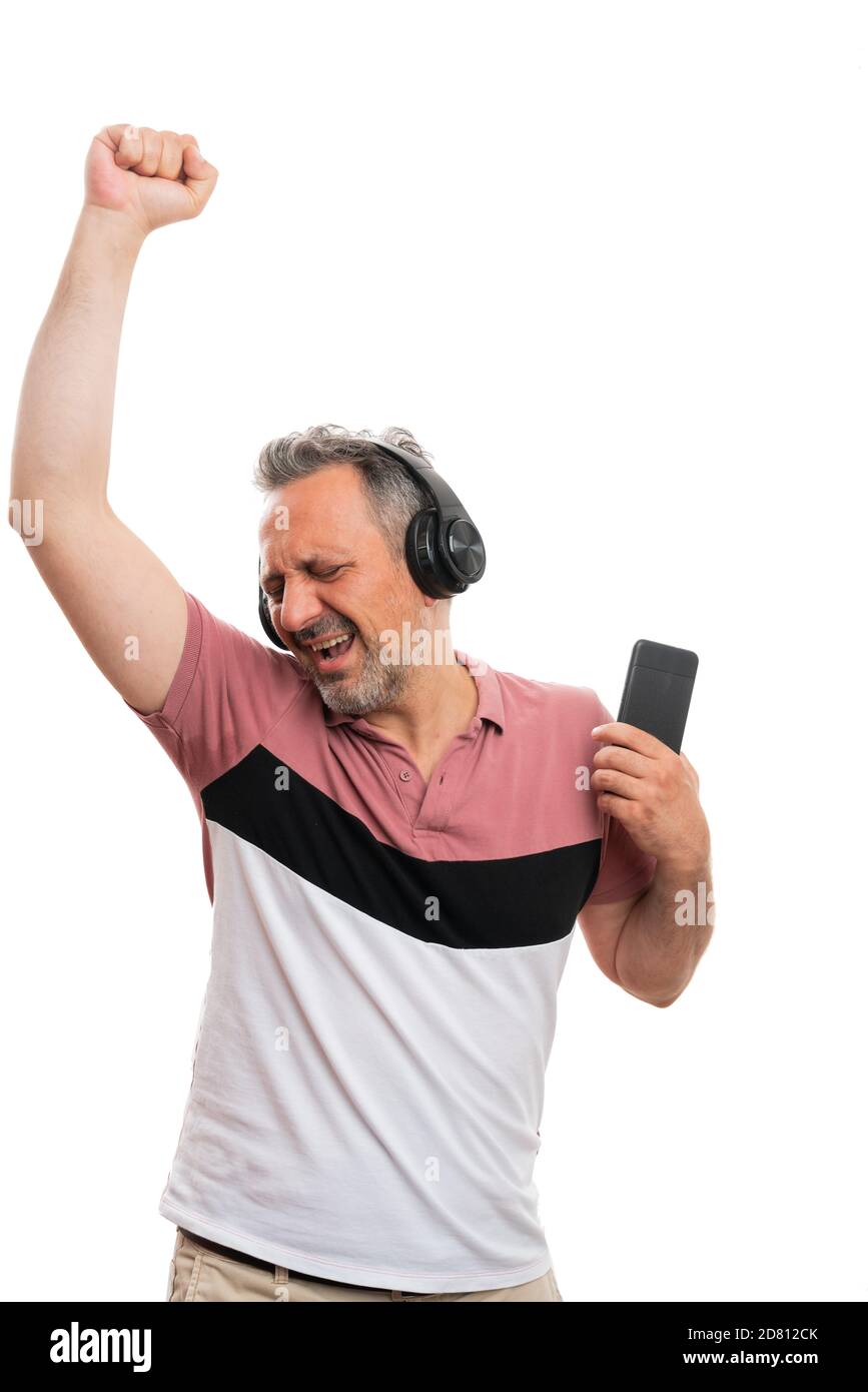 Fröhliche Erwachsene Mann Modell hält Smartphone Musik hören in Kopfhörer genießen Tanz isoliert auf weißem Studio Hintergrund Stockfoto