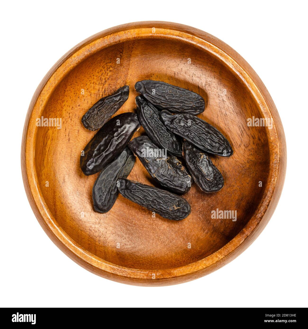Tonkabohnen in einer Holzschüssel. Tonkin oder Tonquinbohnen, schwarze und faltige Samen des Baumes Dipteryx odorata. Natürlicher Cumarin Duft. Stockfoto