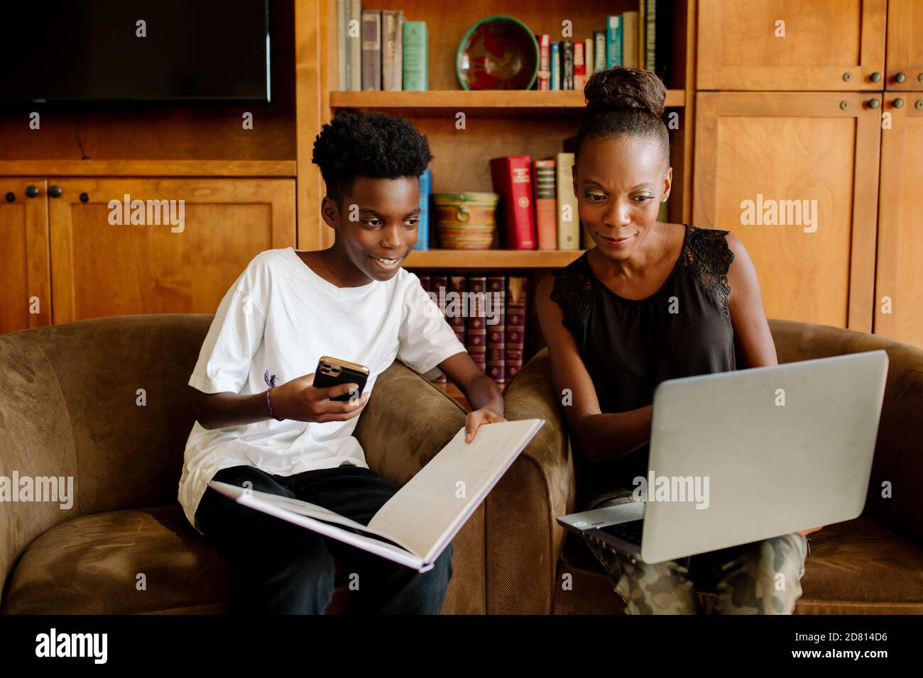 Afroamerikanische Mutter mit Laptop hilft Sohn während Fernunterricht Stockfoto