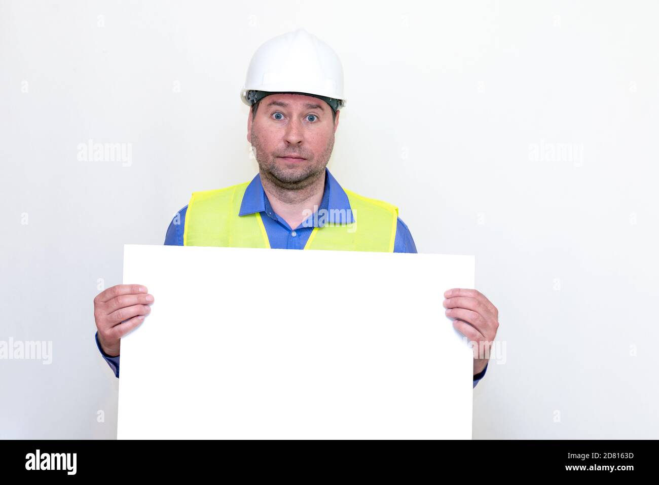 Nahaufnahme Ingenieur Mann trägt einen Helm und Reflektor Weste, stehend und hält eine Plakatwand. Weißer Hintergrund. Stockfoto