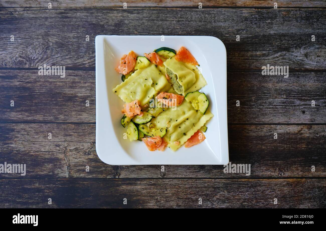 Deutsche Hausmannskost: Maultaschen (gefüllte Pasta - auch „Schwäbische Ravioli“ genannt) mit Lachs und Zucchini. Stockfoto