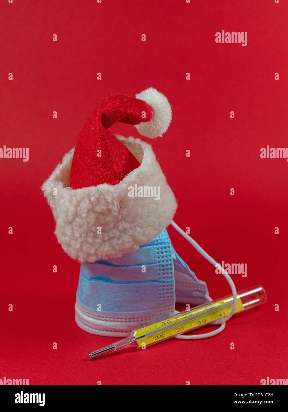 Weihnachtsmann Hut mit Gesichtsmaske und klinischem Thermometer Stockfoto