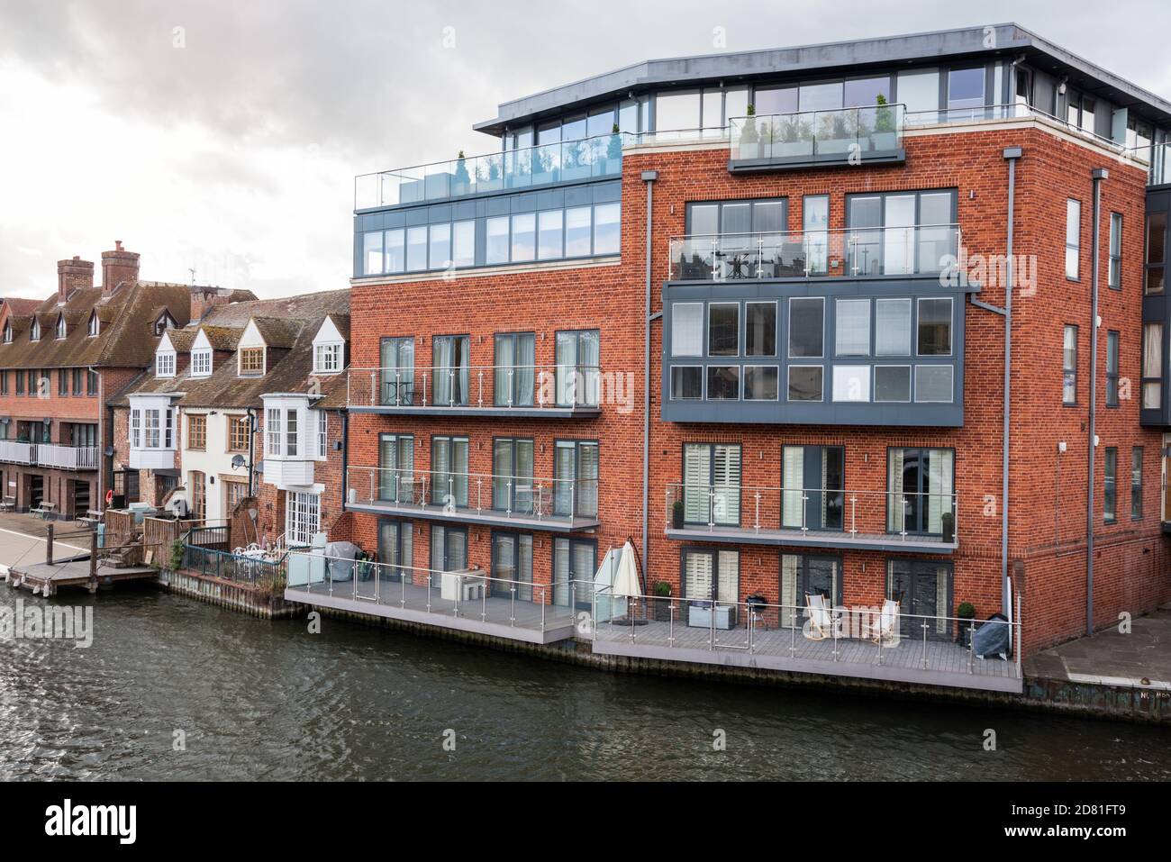 Modernes Apartmentgebäude neben traditionellen britischen Reihenhäusern entlang einer Fluss an einem bewölkten Frühlingstag Stockfoto