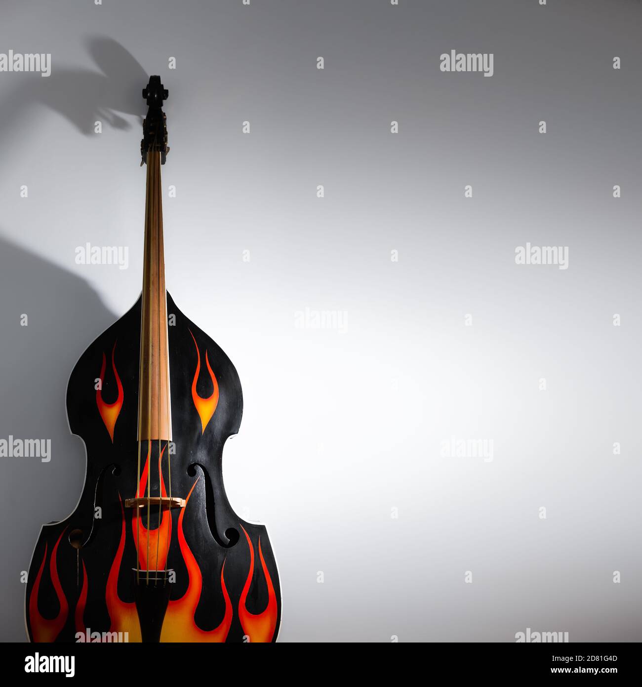 Akustischer Kontrabass mit Flammenabziehbildern, Nahaufnahme. Rock'n'Roll, Rockabilly Musikinstrument im Studio Hintergrund in Low-Key gedreht Stockfoto